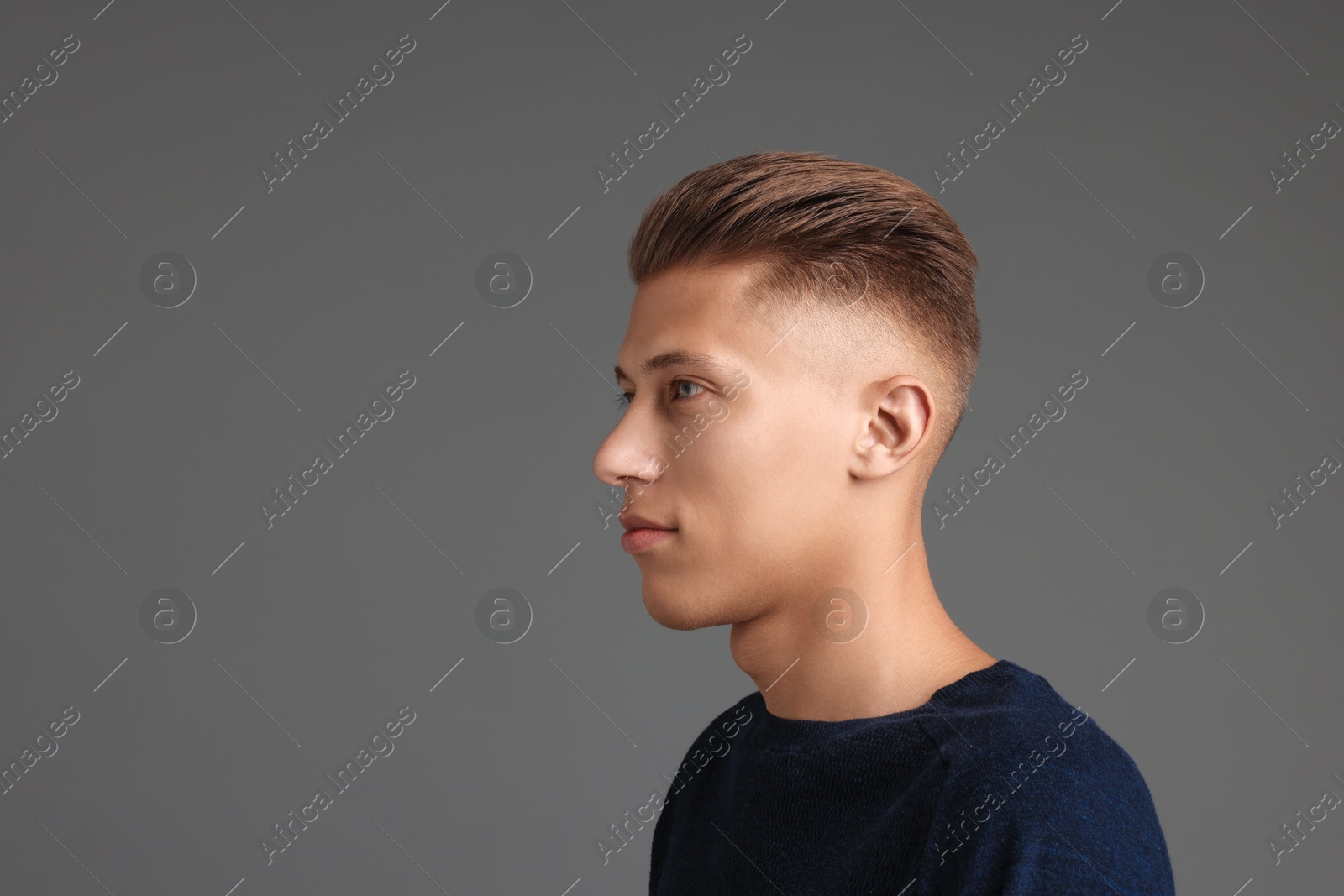 Photo of Handsome young man with stylish haircut on grey background. Space for text