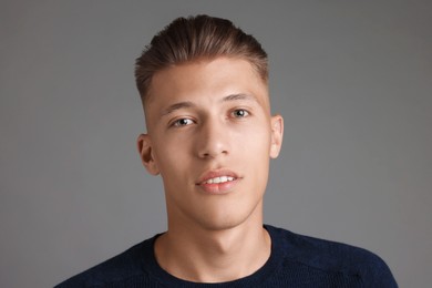 Photo of Handsome young man with stylish haircut on grey background