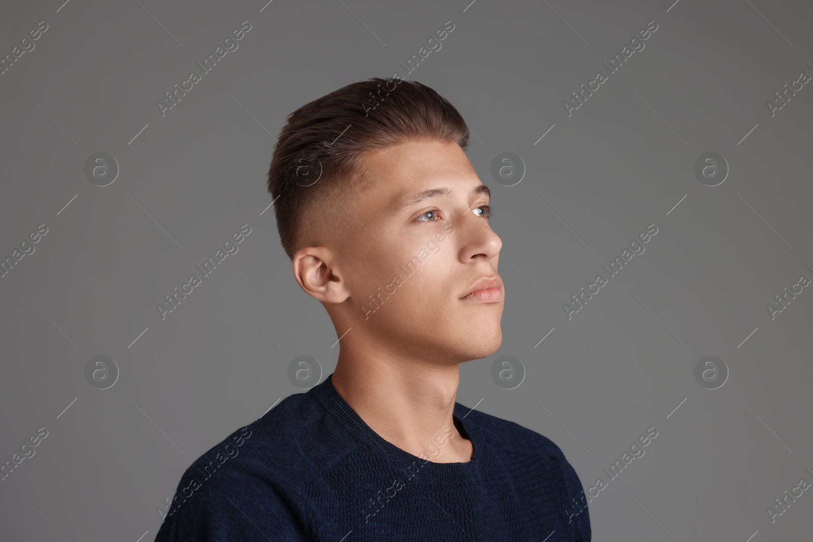 Photo of Handsome young man with stylish haircut on grey background