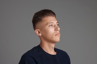 Photo of Handsome young man with stylish haircut on grey background