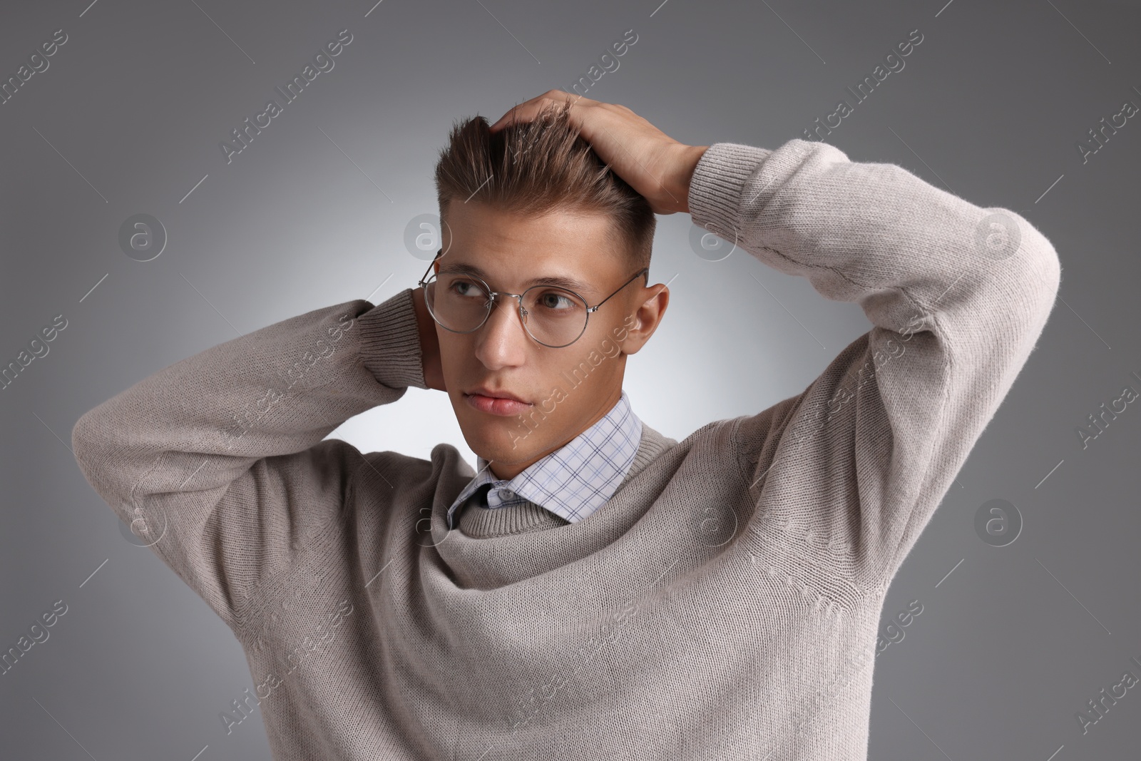 Photo of Handsome young man with stylish haircut on grey background