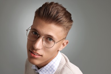 Photo of Handsome young man with stylish haircut on grey background