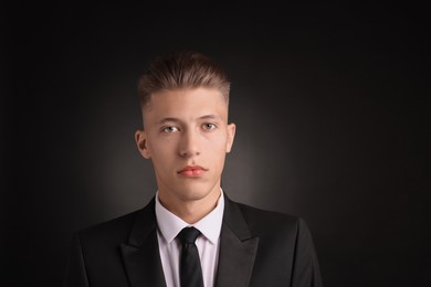 Photo of Confident young man with stylish haircut on black background