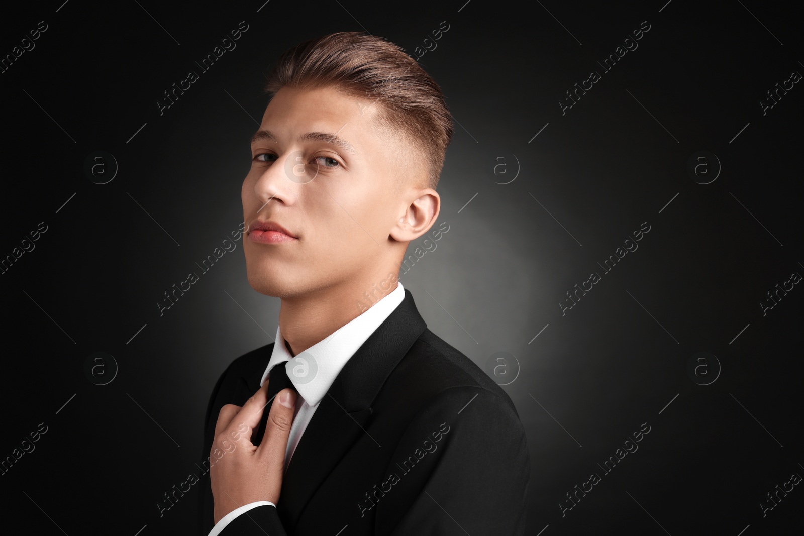 Photo of Confident young man with stylish haircut on black background. Space for text