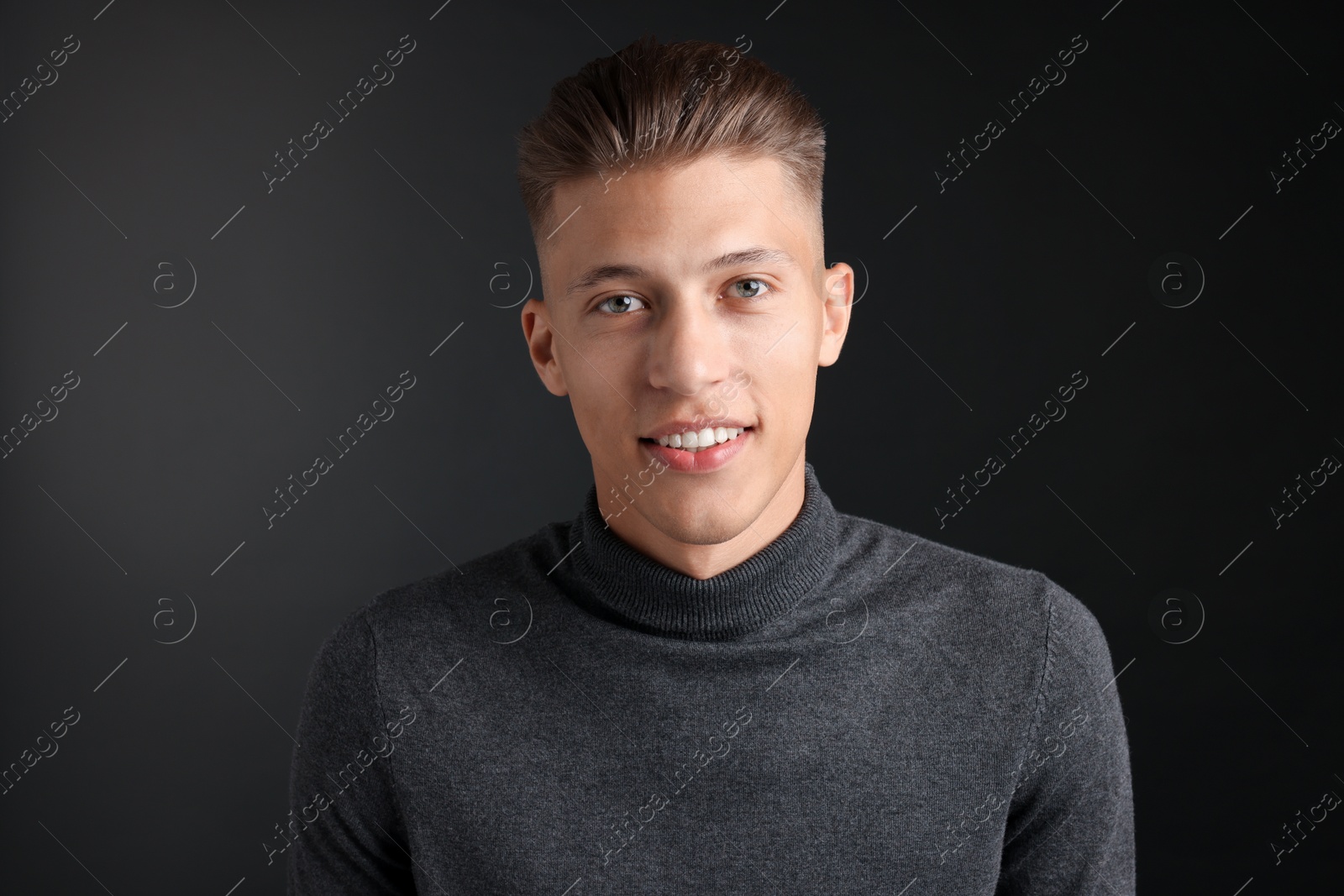 Photo of Handsome young man with stylish haircut on black background