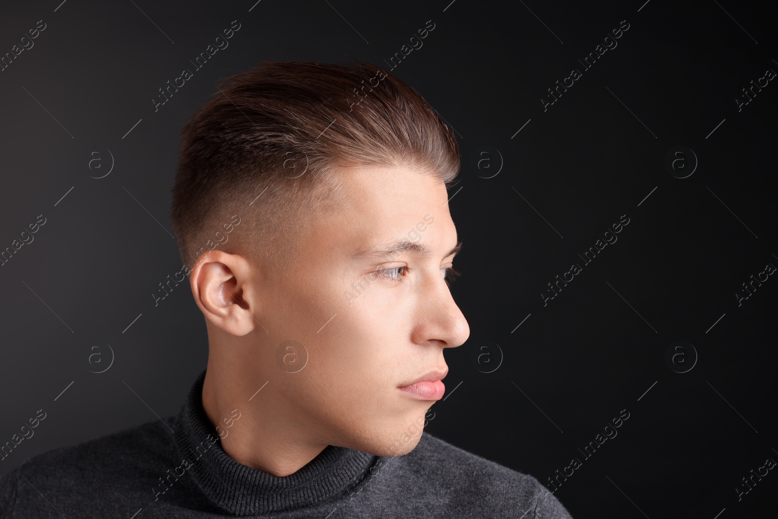 Photo of Handsome young man with stylish haircut on black background