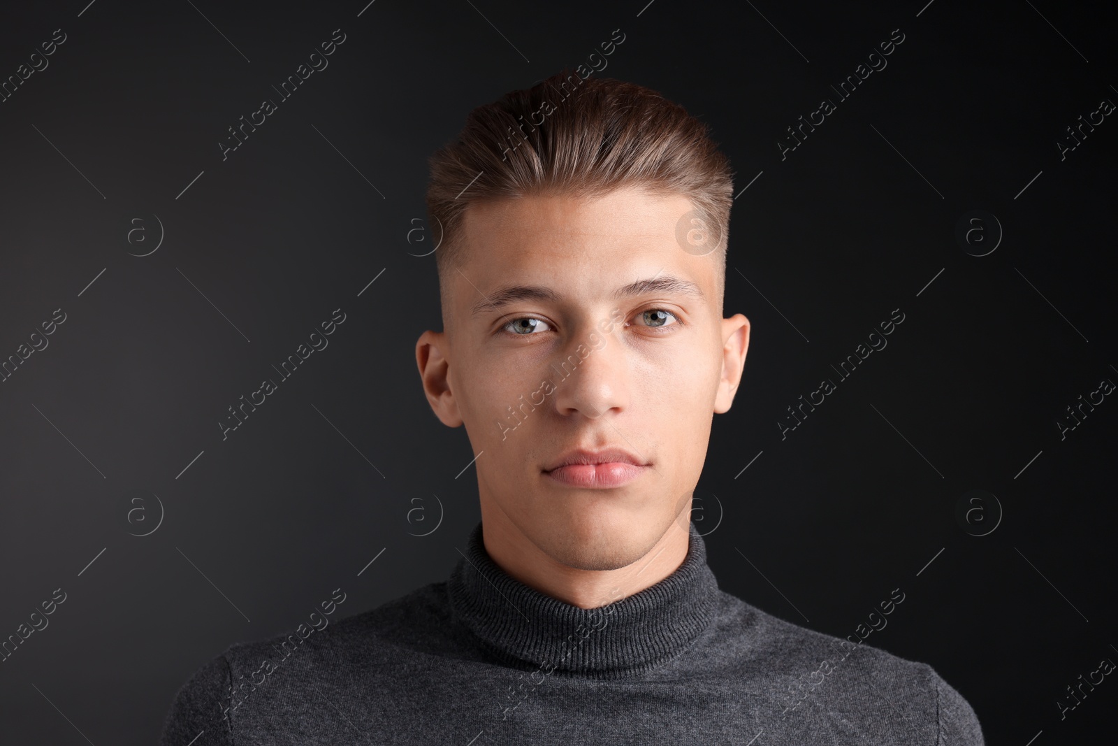 Photo of Handsome young man with stylish haircut on black background