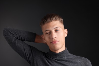 Photo of Confident young man with stylish haircut on black background