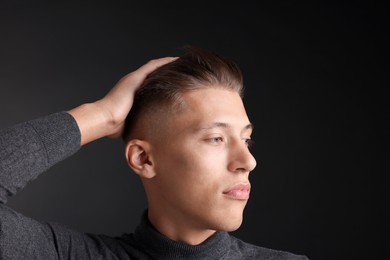 Photo of Confident young man with stylish haircut on black background