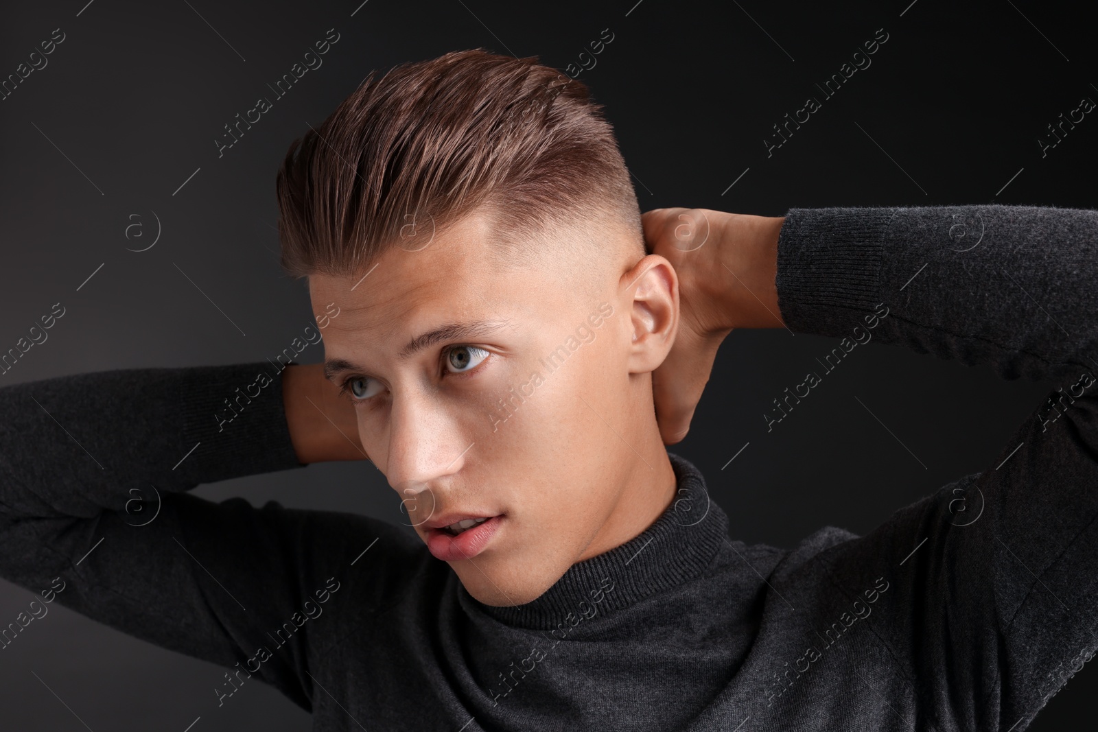 Photo of Confident young man with stylish haircut on black background