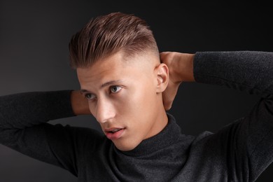 Photo of Confident young man with stylish haircut on black background