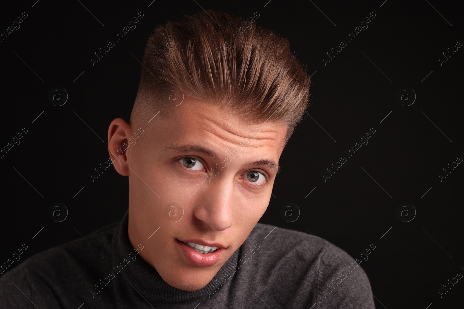 Photo of Confident young man with stylish haircut on black background