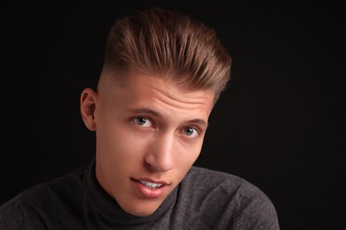 Photo of Confident young man with stylish haircut on black background