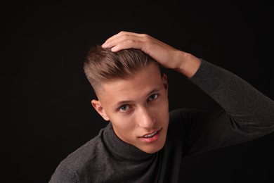 Photo of Confident young man with stylish haircut on black background