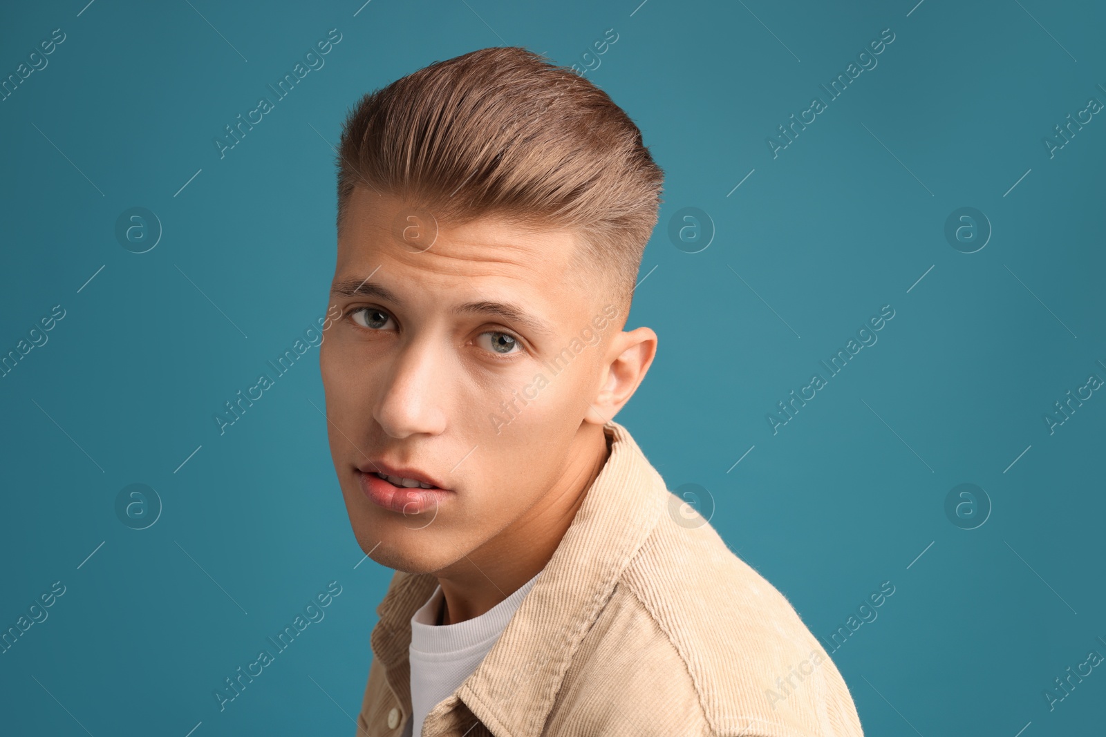 Photo of Confident young man with stylish haircut on blue background