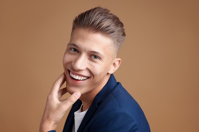 Photo of Confident young man with stylish haircut on brown background