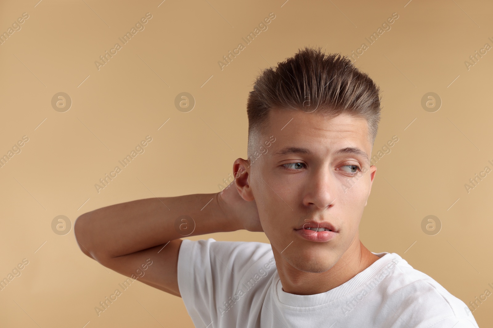 Photo of Confident young man with stylish haircut on light brown background