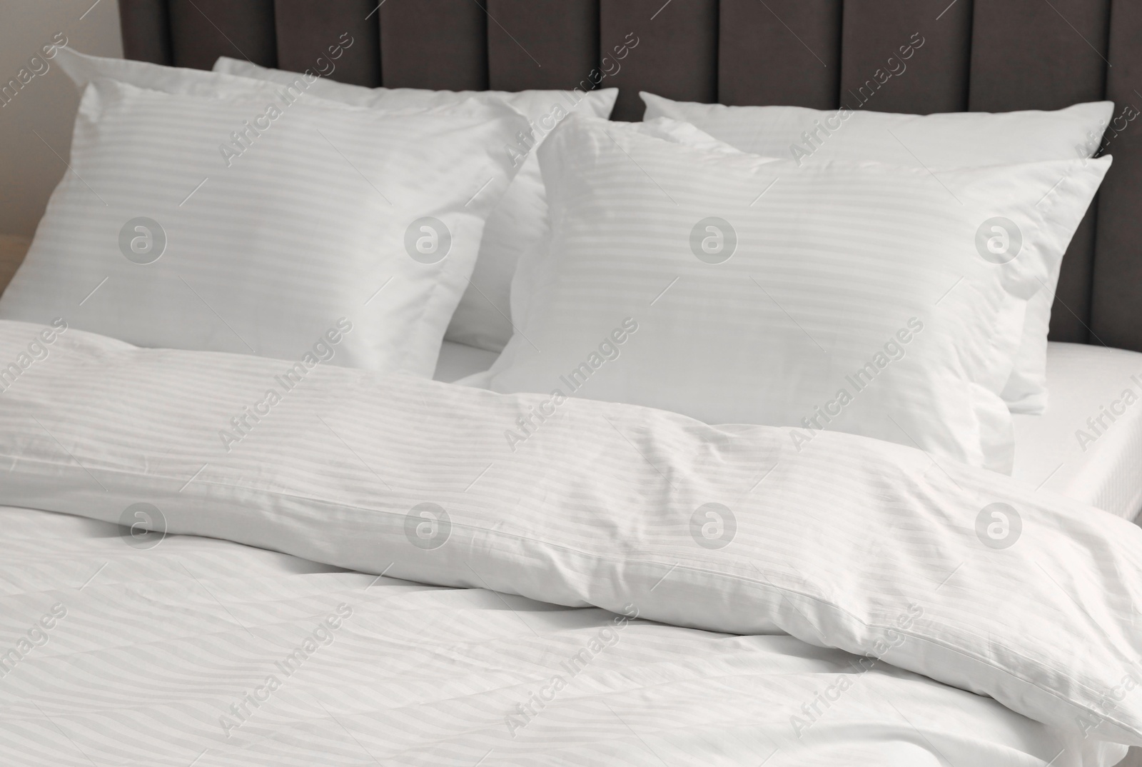 Photo of Bed with clean linens and pillows indoors