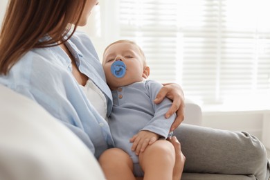 Mother with her sleeping baby on sofa indoors, closeup