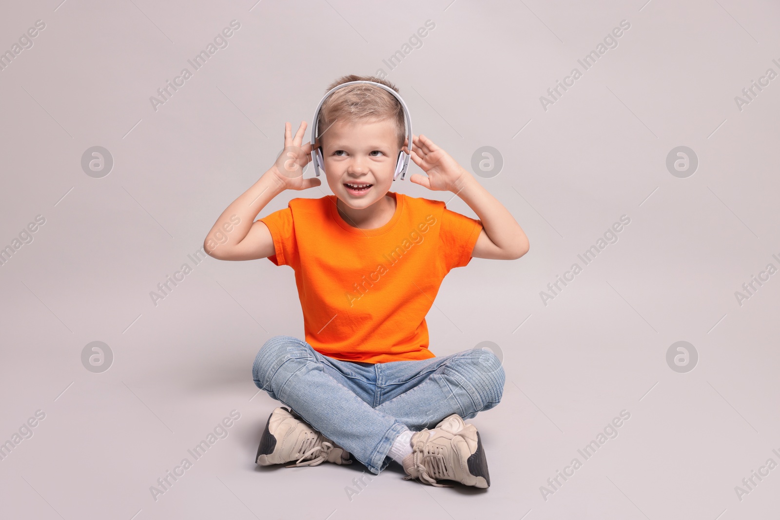 Photo of Little boy listening to music on light grey background