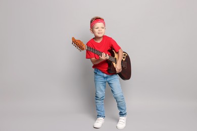 Little boy with guitar on light grey background