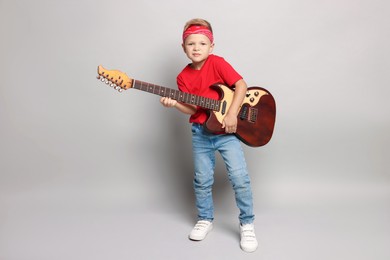 Little boy with guitar on light grey background