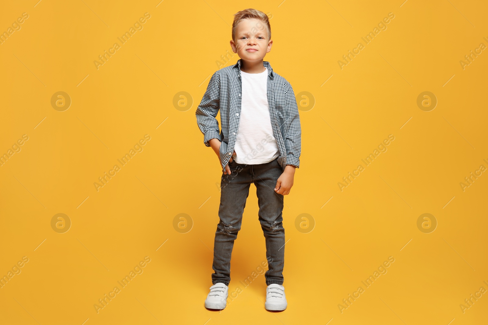 Photo of Full length portrait of little boy with stylish clothes on orange background