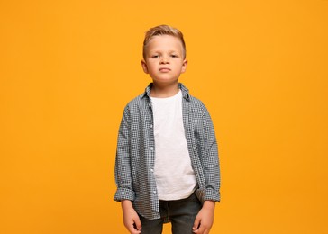 Photo of Portrait of little boy with stylish clothes on orange background