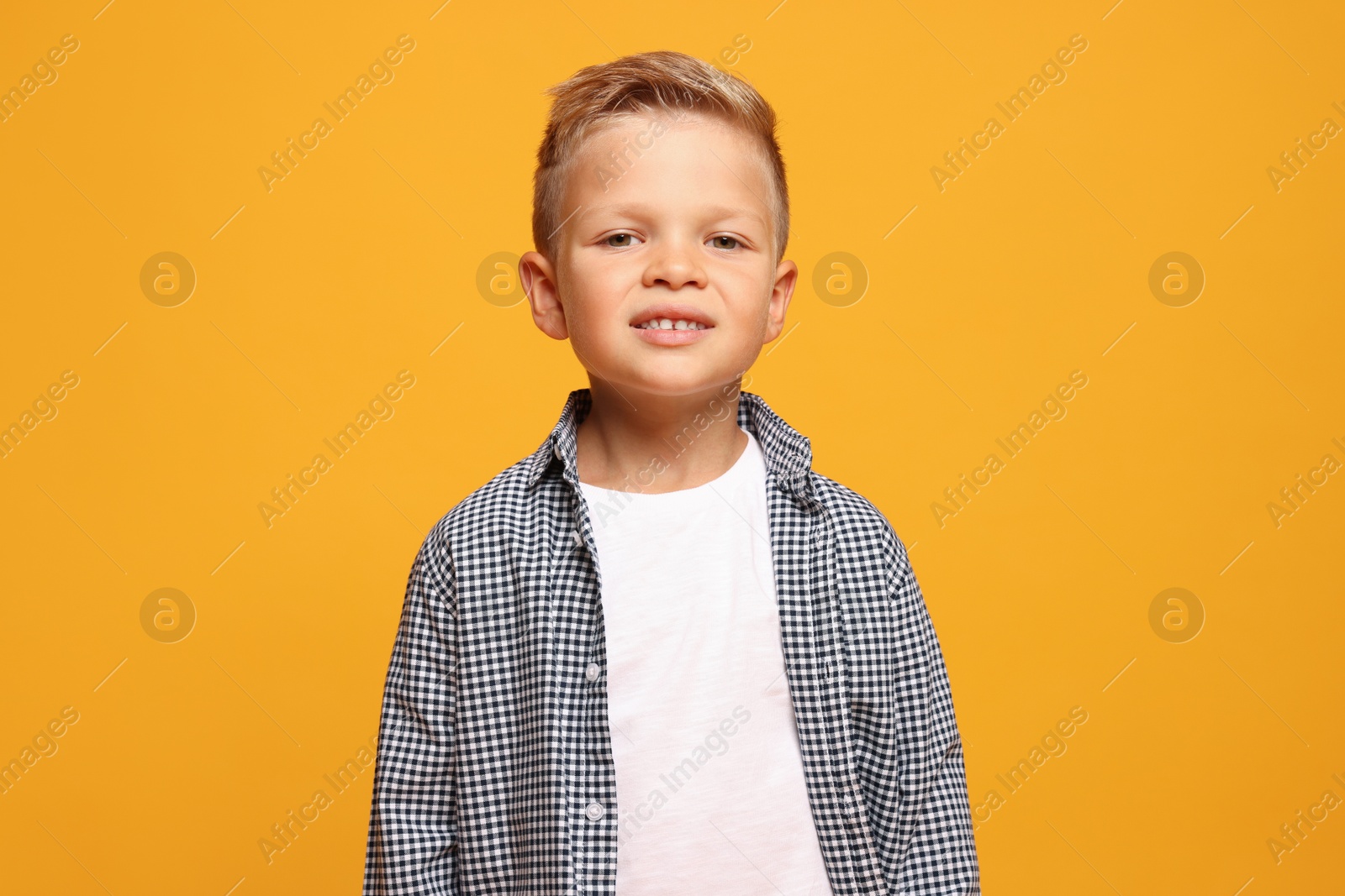 Photo of Portrait of little boy with stylish clothes on orange background