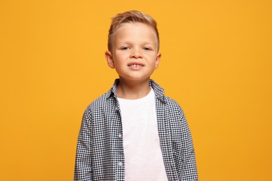 Portrait of little boy with stylish clothes on orange background