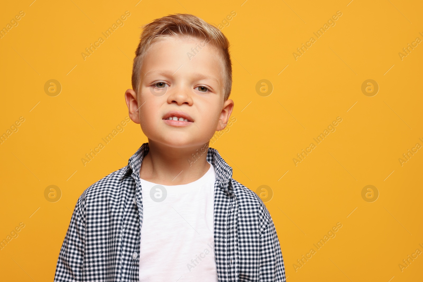 Photo of Portrait of little boy with stylish clothes on orange background