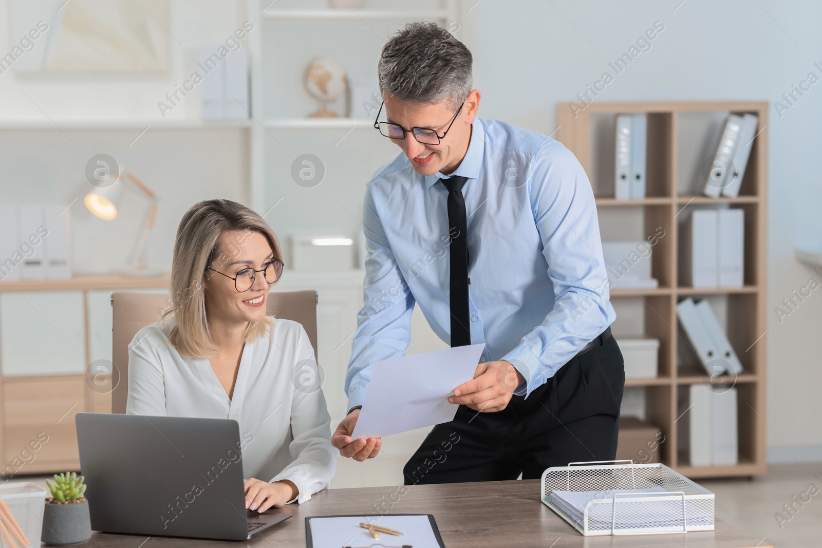 Photo of Middle aged employees working together in office