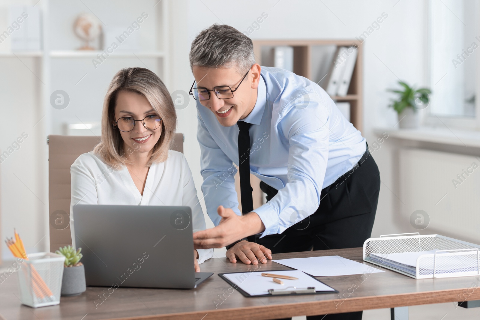 Photo of Middle aged employees working together in office