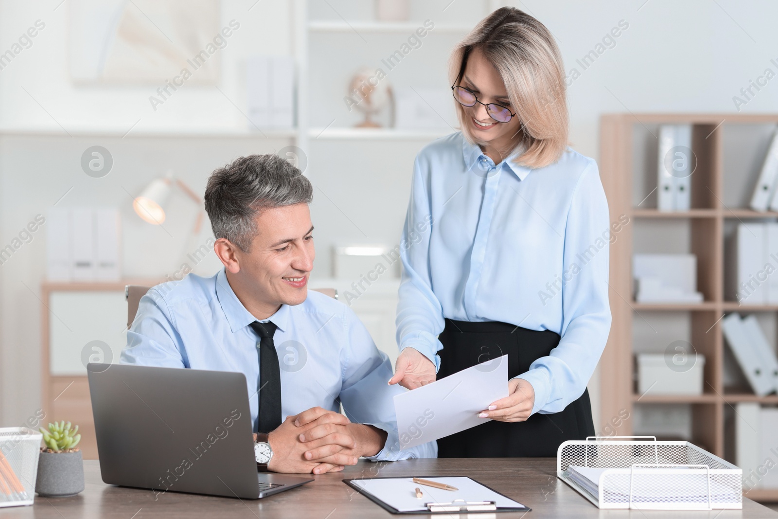 Photo of Middle aged employees working together in office