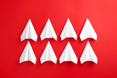 Photo of White paper planes on red background, top view