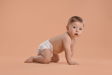 Photo of Cute little baby in diaper crawling on beige background