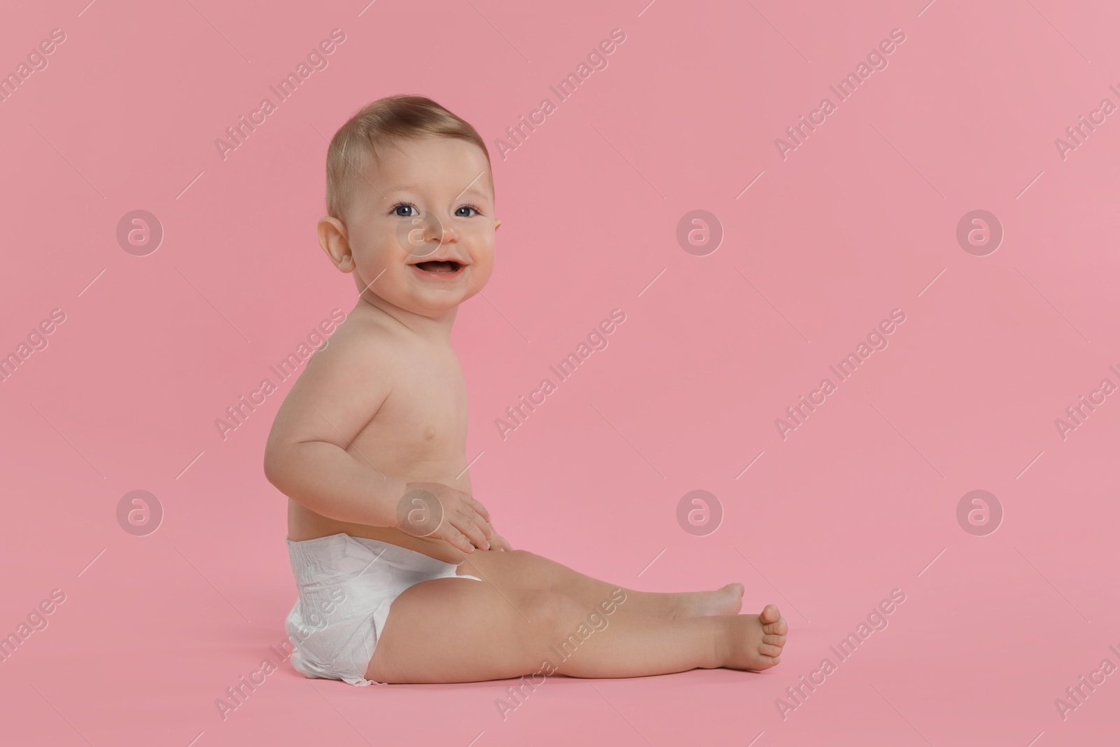 Photo of Cute little baby in diaper sitting on pink background