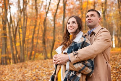 Photo of Happy couple spending time together in autumn park, space for text