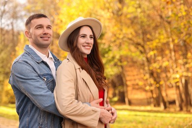 Photo of Happy couple spending time together in autumn park, space for text