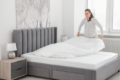 Photo of Woman changing clean bed linens at home