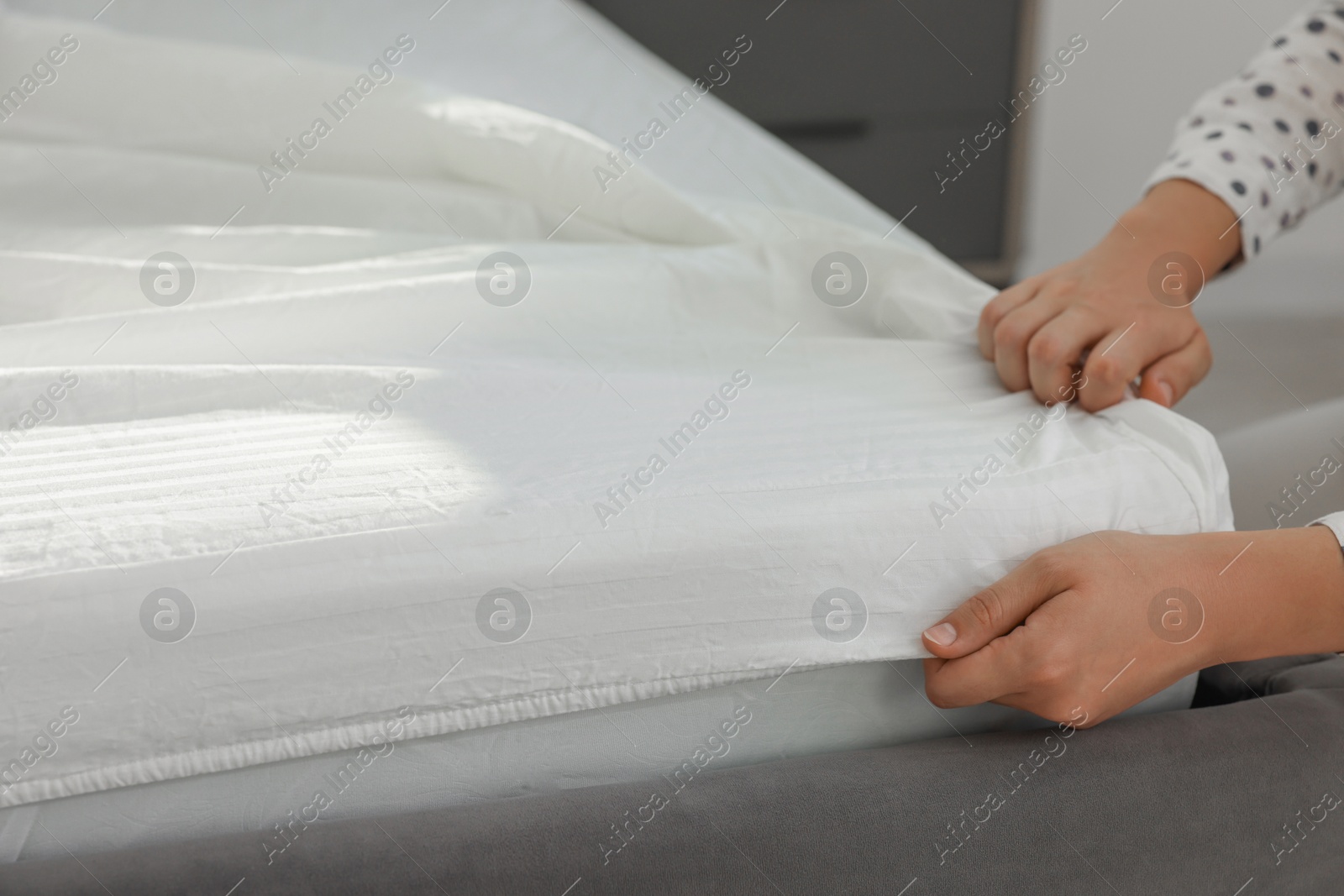 Photo of Woman changing clean bed linens at home, closeup