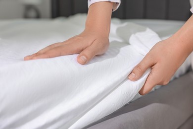 Photo of Woman changing clean bed linens at home, closeup