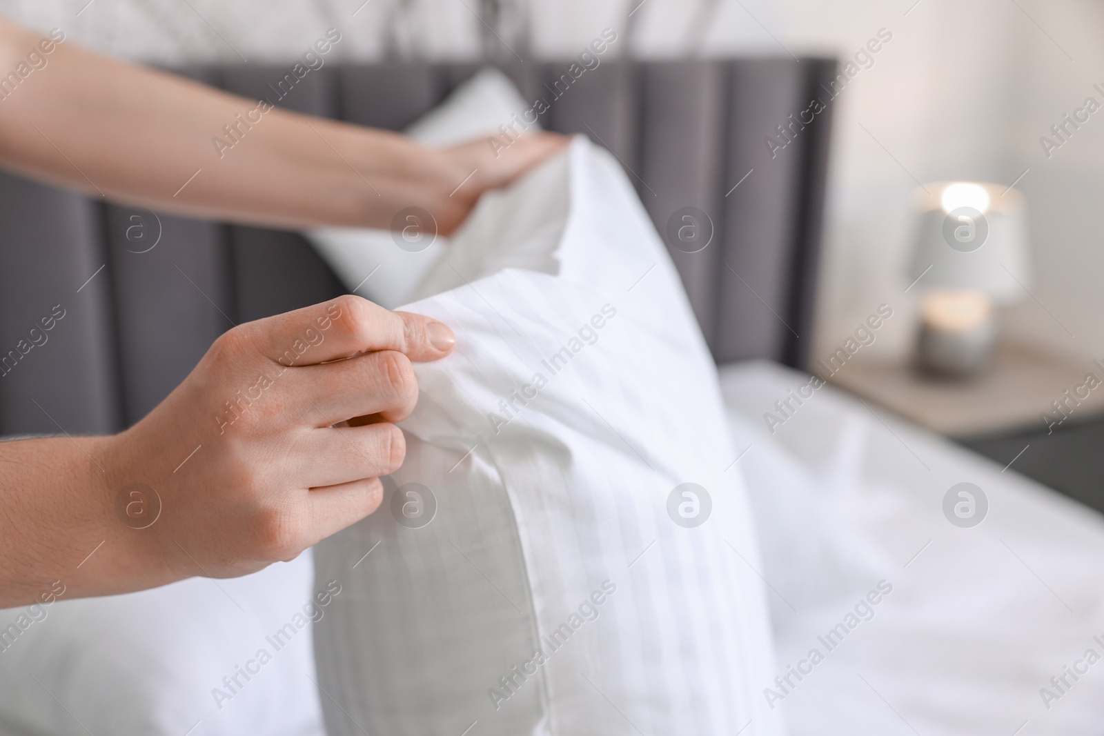 Photo of Woman changing clean bed linens at home, closeup