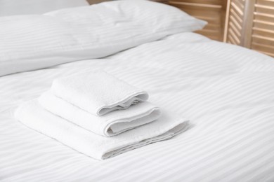 Photo of Bed with clean linens and towels indoors