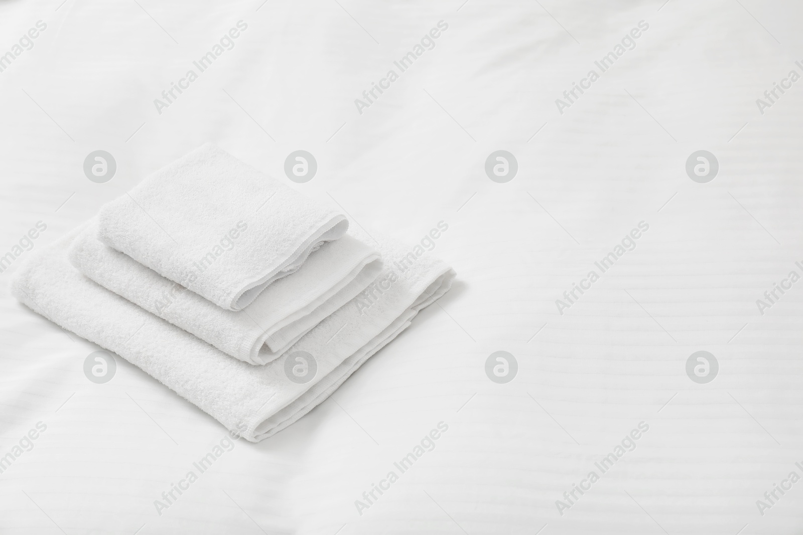 Photo of Stack of towels on clean linens indoors, space for text