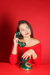 Photo of Woman talking on green vintage telephone against red background