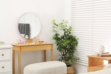 Photo of Mirror, dressing table, houseplant and chest of drawers indoors. Interior design