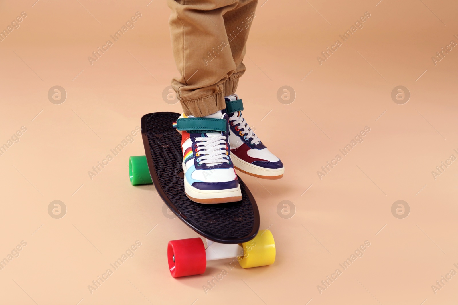 Photo of Little boy with skateboard on beige background, closeup