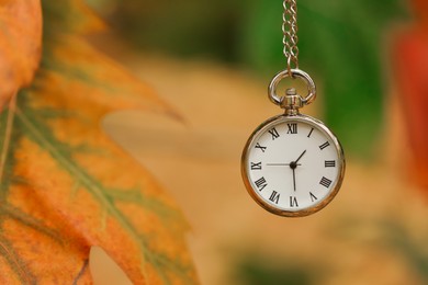 Photo of Autumn time. Chain watch on blurred background, closeup with space for text