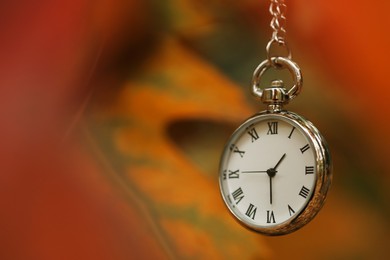 Photo of Autumn time. Chain watch on blurred background, closeup with space for text